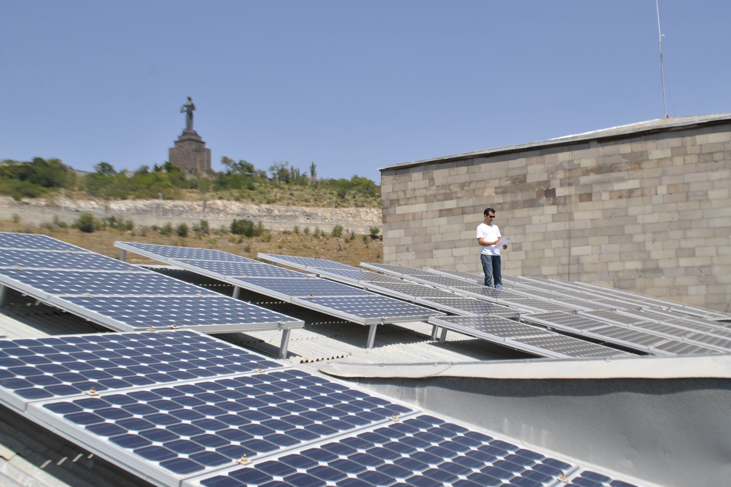 Solar Panels in grassy sunny area, person stands at the back